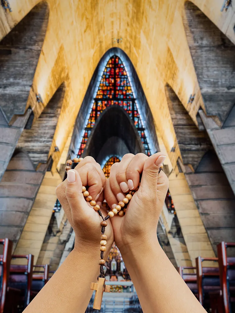 Foto pie: Manos sosteniendo un rosario frente al altar de la basílica. Crédito: Instagram Basílica-Catedral Nuestra Señora de la Altagracia.